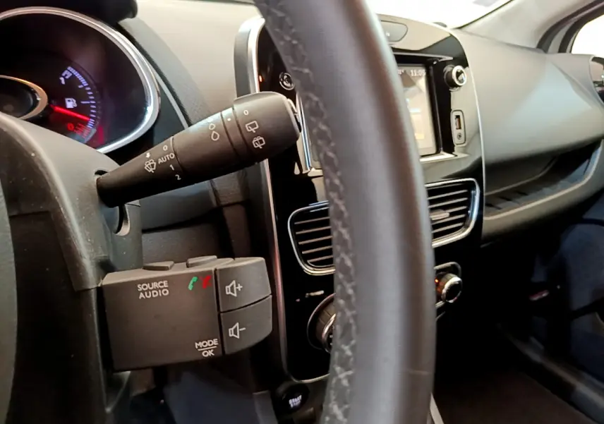 Détail intérieur du volant cuir et commandes audio de la Renault Clio Business TCe 90 2019, tableau de bord et écran tactile visibles.