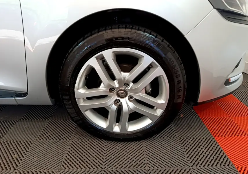 Gros plan sur la roue avant droite gris clair d'une Renault Clio Business TCe 90 avec jante alliage et logo Renault central.