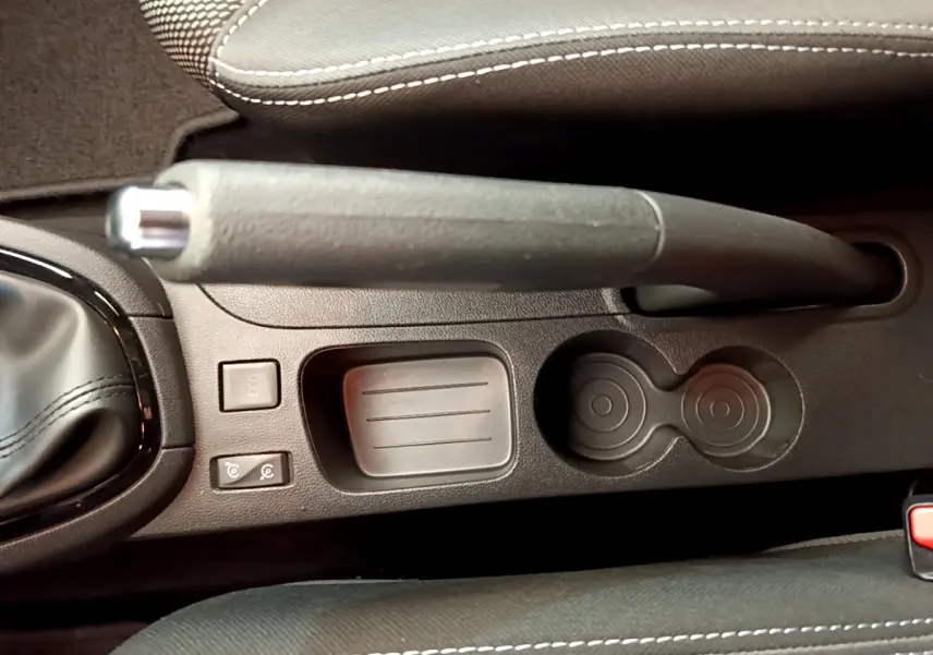 Gros plan sur le frein à main et la console centrale noire de la Renault Clio Business TCe 90, avec porte-gobelets et boutons de contrôle.
