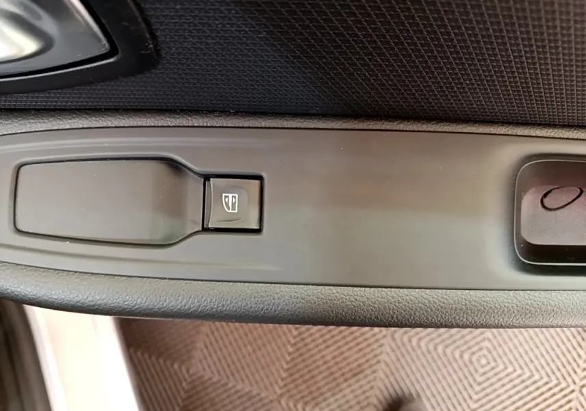 Gros plan sur le bouton de commande de la vitre électrique côté conducteur de la Renault Clio Business gris clair.