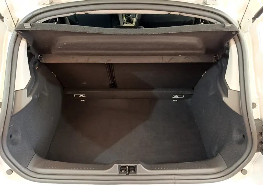 Coffre ouvert vu de l'arrière d'une Renault Clio Business TCe 90 gris clair, montrant l'espace de chargement vide.