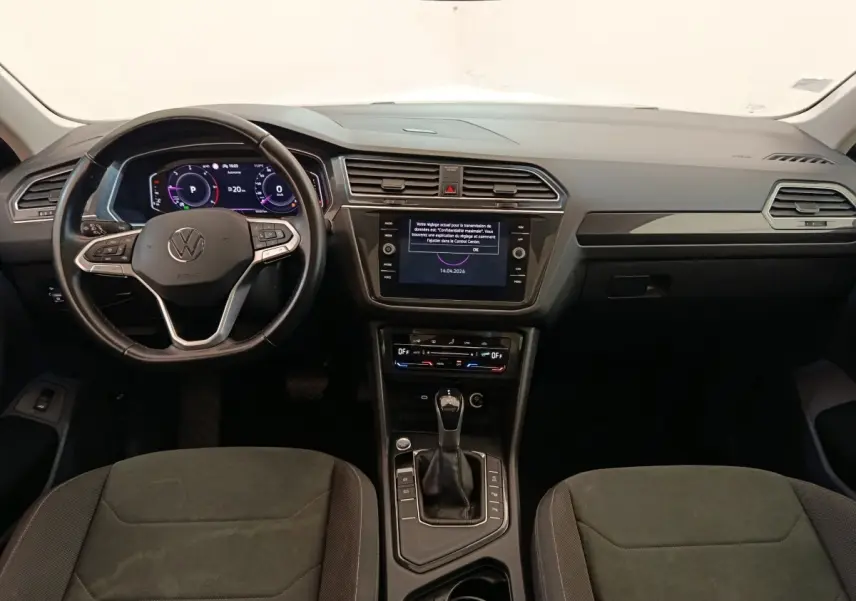 Vue intérieure avant du Volkswagen Tiguan 2.0 TDI 2022, tableau de bord noir avec écran tactile et volant cuir multifonctions.