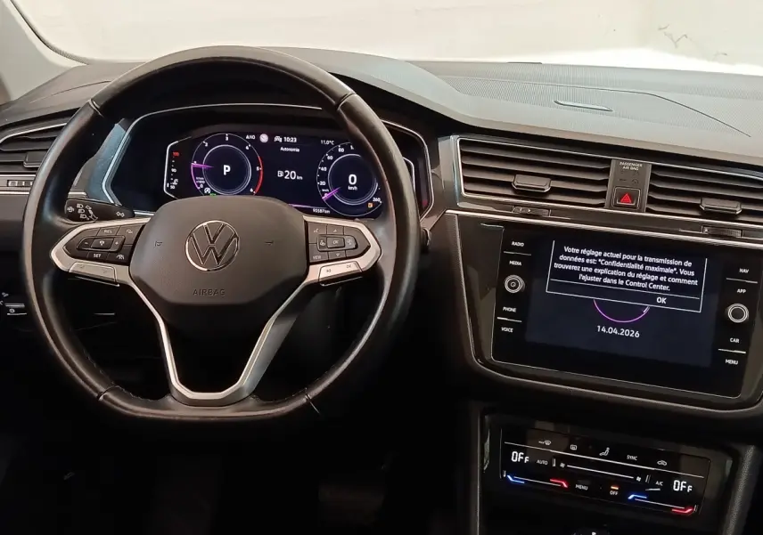 Vue intérieure centrée sur le volant cuir noir et l’écran tactile du tableau de bord du Volkswagen Tiguan 2022.