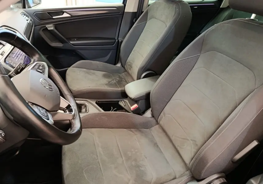 Vue intérieure rapprochée du Volkswagen Tiguan 2.0 TDI 150 DSG7 Elegance, sièges avant en tissu gris et volant cuir noir.