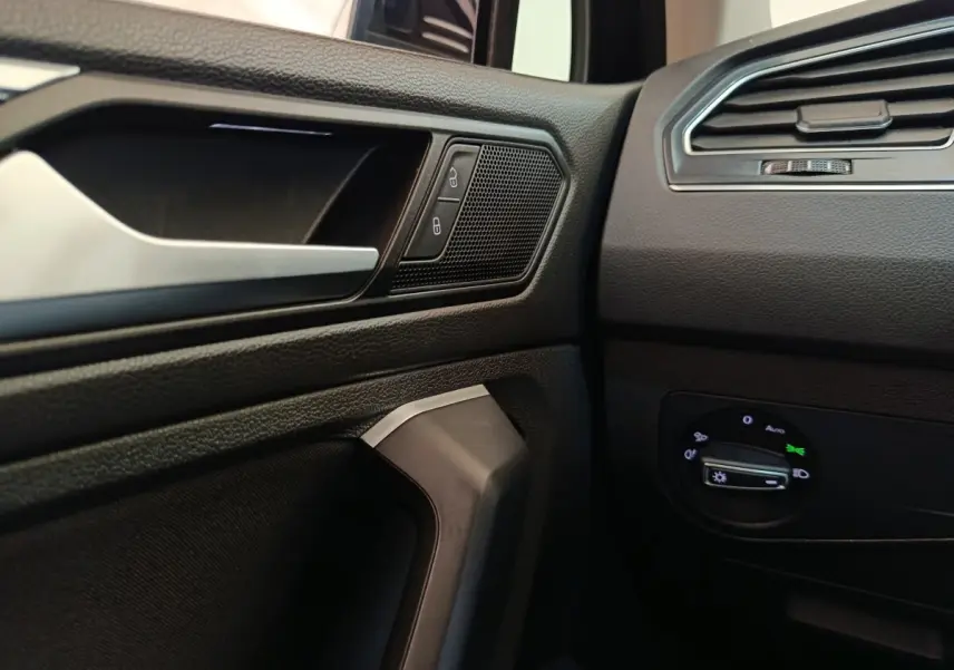 Détail intérieur côté conducteur du Volkswagen Tiguan 2022 noir, avec commandes de verrouillage et réglage phares.