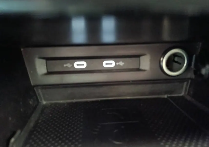 Gros plan sur la zone de recharge sans fil avec deux ports USB et prise 12V du Volkswagen Tiguan noir 2022.