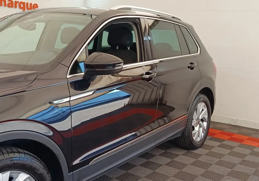 Vue côté gauche du Volkswagen Tiguan noir 2022, mettant en valeur les jantes alliage et les rétroviseurs avec clignotants intégrés.