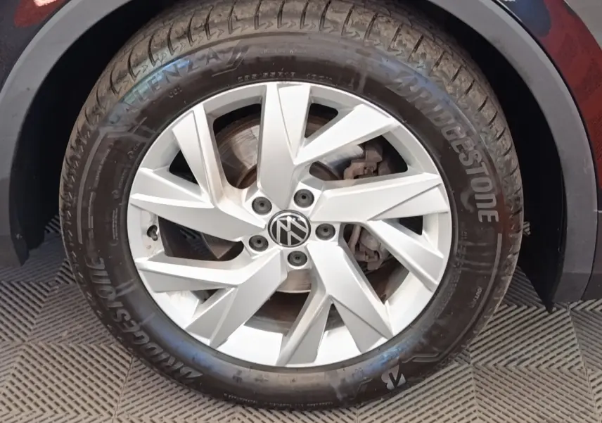 Gros plan sur la roue avant droite du Volkswagen Tiguan noir, jante alliage argentée avec logo VW central.