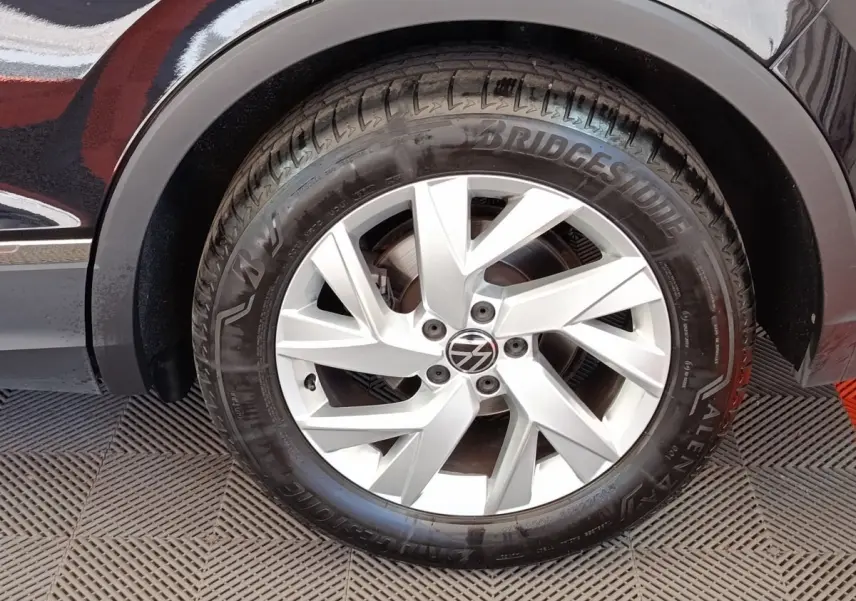 Gros plan sur la roue avant droite d’un Volkswagen Tiguan noir, jante alliage argentée à design moderne.