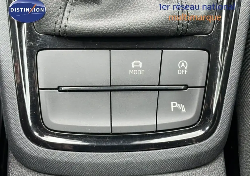Gros plan sur les boutons de commande du mode de conduite et assistance au stationnement dans une Skoda Kamiq blanc glacier 2025.