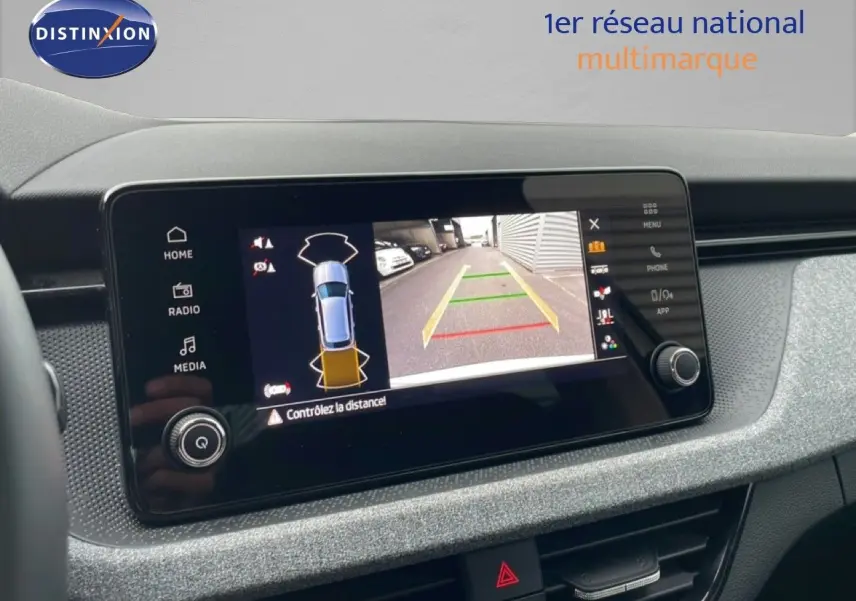 Écran central affichant la caméra de recul avec vue arrière et alertes de distance dans un Skoda Kamiq blanc glacier.