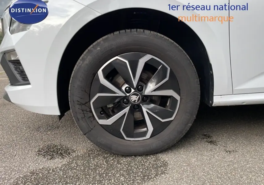 Gros plan sur la roue avant gauche et l'aile d'une Skoda Kamiq blanc glacier, mettant en valeur la jante noire et argentée.