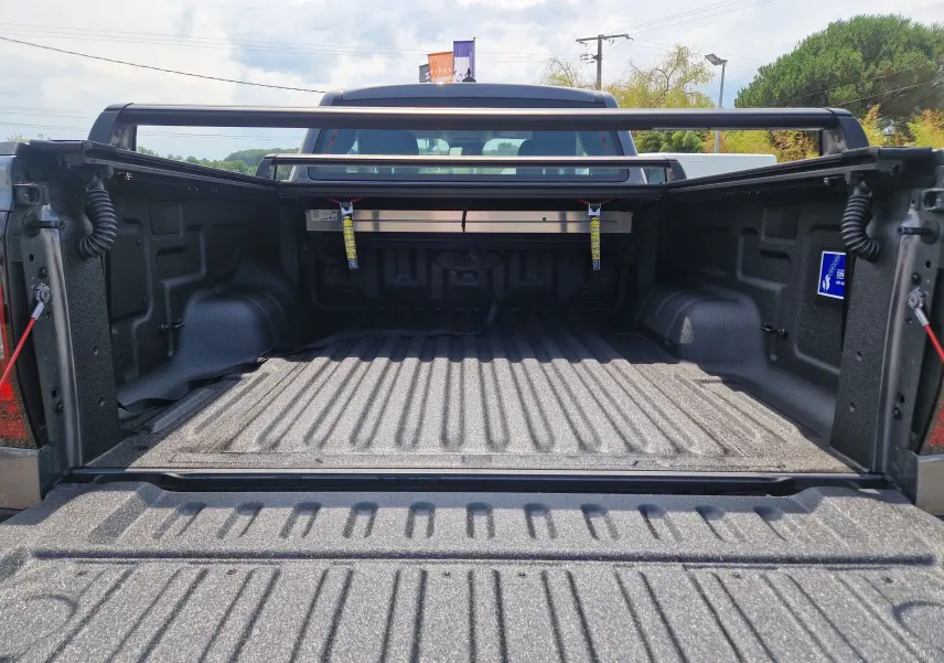Vue arrière du plateau ouvert du Ford Ranger Super Cabine gris carbone, avec rideau rigide coulissant et protection renforcée.