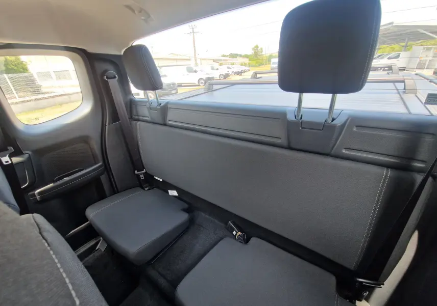 Vue intérieure arrière du Ford Ranger Super Cabine gris carbone, montrant les sièges arrière rabattables et le rideau de plateau rigide.