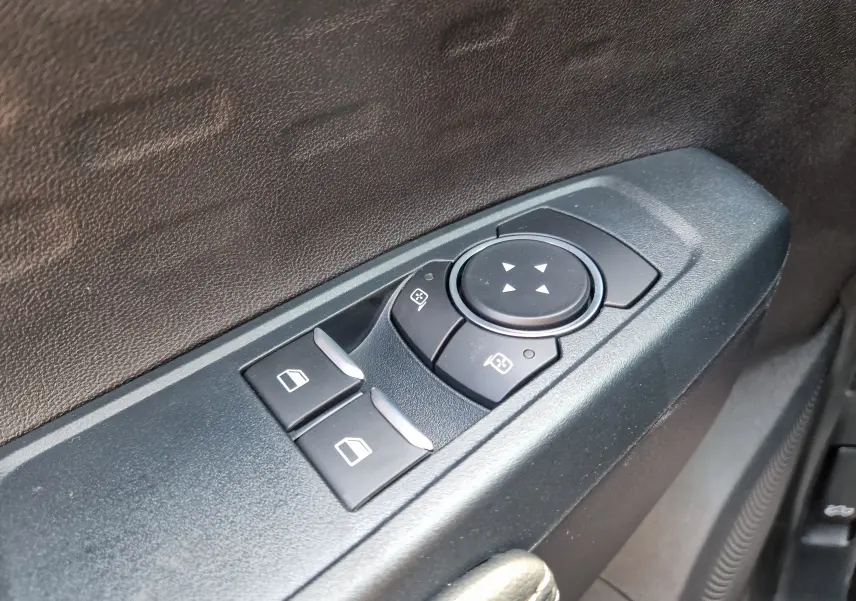 Gros plan sur les commandes électriques des vitres et rétroviseurs côté conducteur du Ford Ranger Super Cabine gris carbone.