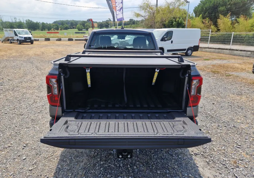 Vue arrière du Ford Ranger Super Cabine gris carbone avec plateau ouvert et rideau rigide coulissant visible.