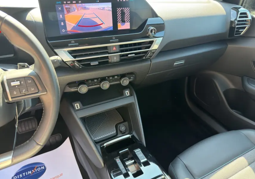 Vue intérieure côté conducteur du tableau de bord noir du Citroën C4 2023 avec écran tactile et volant cuir multifonctions.