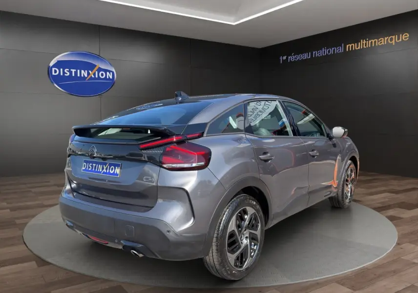 Vue 3/4 arrière droite d'une Citroën C4 gris foncé 2023 avec feux LED et spoiler de coffre visible.
