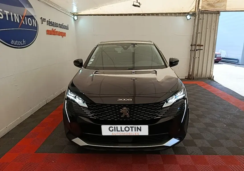 Peugeot 3008 noir vue de face dans un garage, avec calandre distinctive et feux LED allumés.