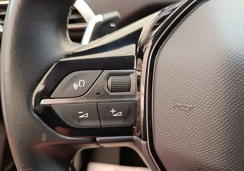 Gros plan sur les commandes gauche du volant cuir noir du Peugeot 3008 PureTech 130 Allure 2022.