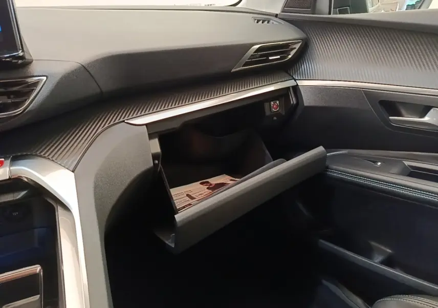 Intérieur du Peugeot 3008 PureTech 130 2022, vue côté passager sur boîte à gants ouverte et tableau de bord noir texturé.