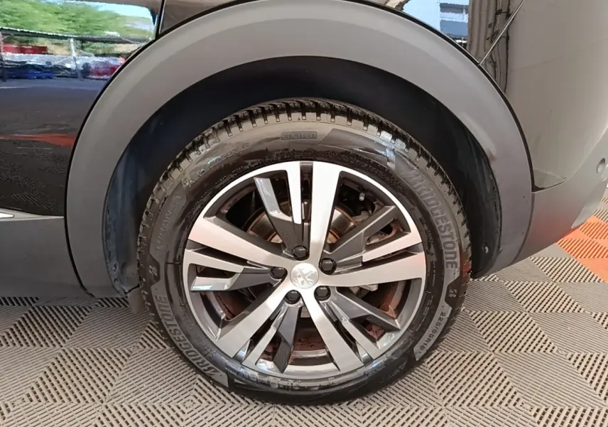 Gros plan sur la roue arrière droite d’un Peugeot 3008 noir, mettant en valeur la jante alliage moderne et le pneu Bridgestone.