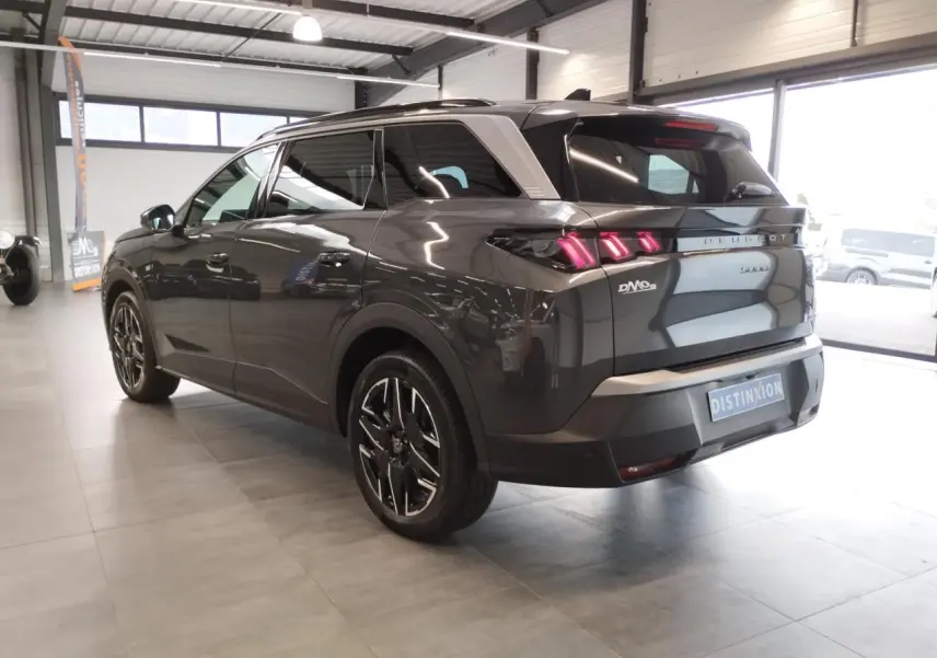 Peugeot 5008 gris titanium vue 3/4 arrière droit en intérieur avec feux arrière LED 3 griffes allumés.
