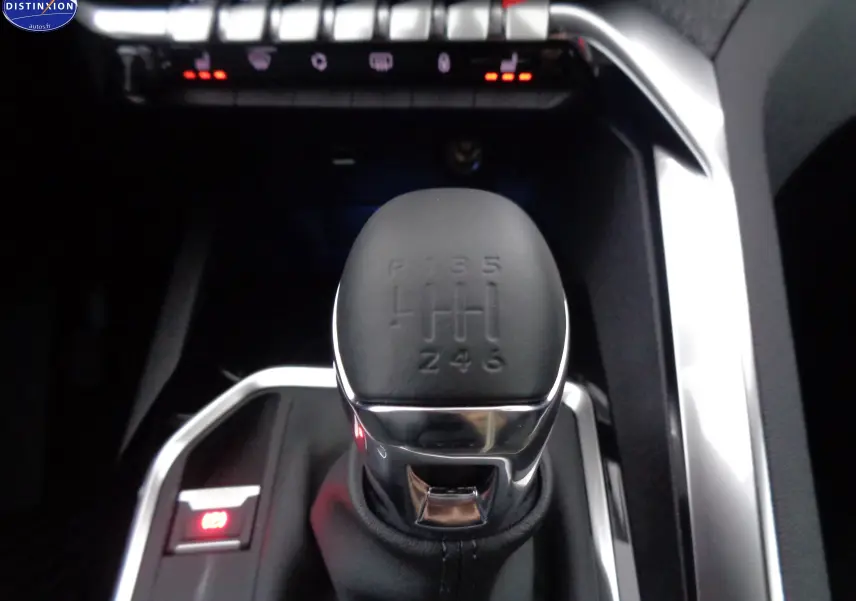 Le levier de vitesses manuel de la Peugeot 3008 2023 en gros plan, entouré de finitions chromées et boutons lumineux.
