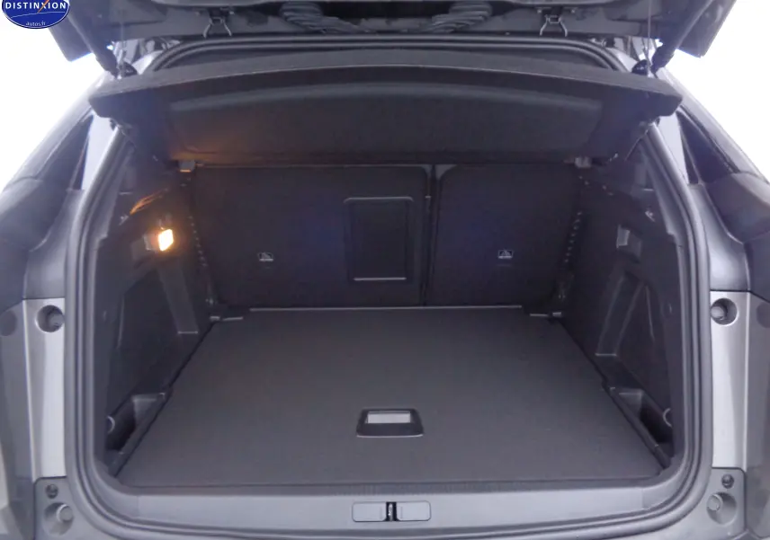 Coffre ouvert vu de l'arrière d'un Peugeot 3008 gris platinium métal, montrant un espace de chargement spacieux et propre.
