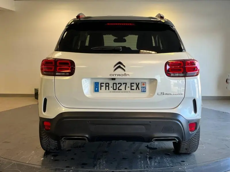 Vue arrière d'un SUV Citroën C5 Aircross blanc nacré avec feux LED et attelage visible en intérieur neutre.