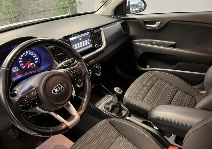 Vue intérieure côté conducteur du Kia Stonic 2019, volant cuir, console centrale avec écran tactile et levier de vitesse manuel.