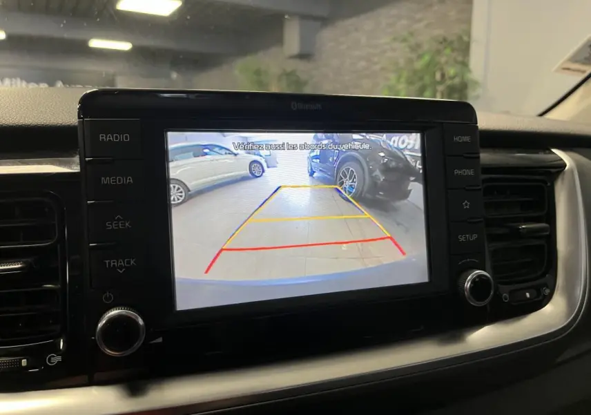 Écran tactile 7'' de la Kia Stonic blanc montrant la caméra de recul avec lignes de guidage actives.