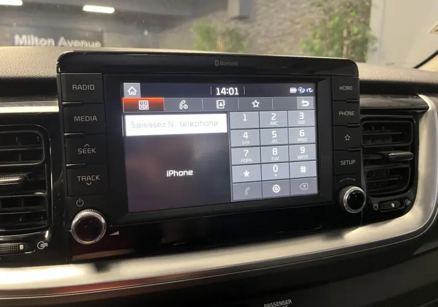 Écran tactile central du tableau de bord du Kia Stonic blanc 2019, avec interface Bluetooth et commandes autour.