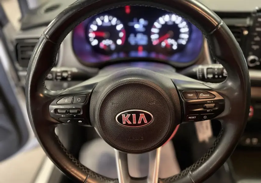 Gros plan sur le volant cuir noir du Kia Stonic 2019 avec commandes intégrées et logo central rouge.