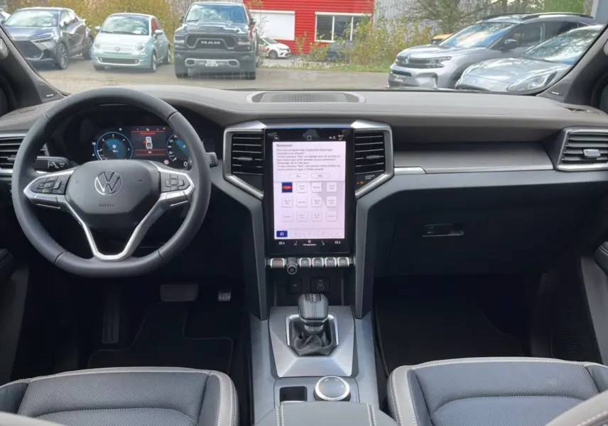 Vue intérieure du tableau de bord du Volkswagen Amarok Simple Cabine noir 2025 avec écran tactile vertical et volant multifonction.