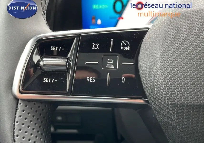 Gros plan sur les commandes au volant noir perforé du Renault Espace 2025, avec écran digital en arrière-plan.