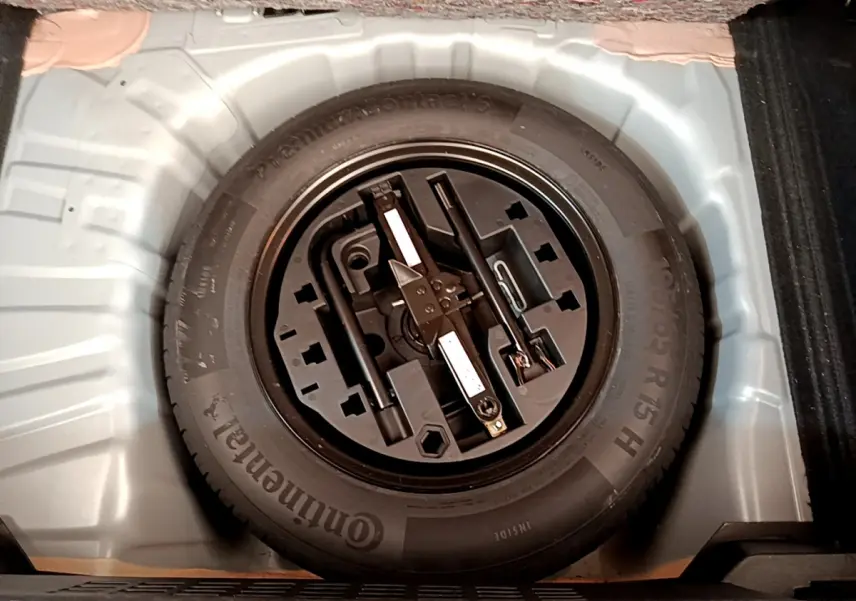 Roue de secours noire avec outils intégrés dans le coffre gris clair d'une Renault Clio Business TCe 100 2020.