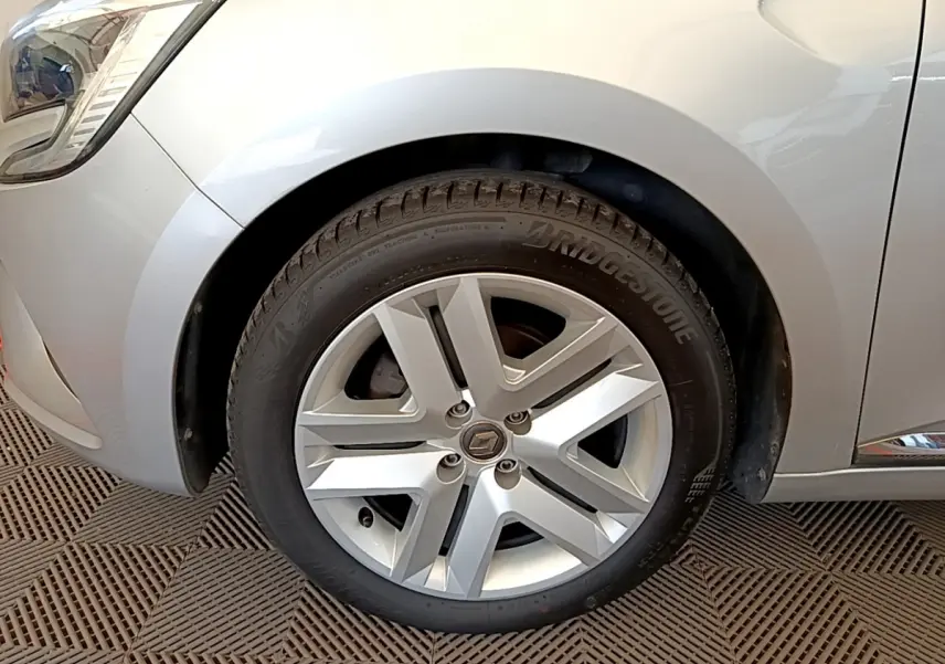 Gros plan sur la roue avant gauche gris clair d'une Renault Clio Business TCe 100 avec jante alliage à cinq branches.