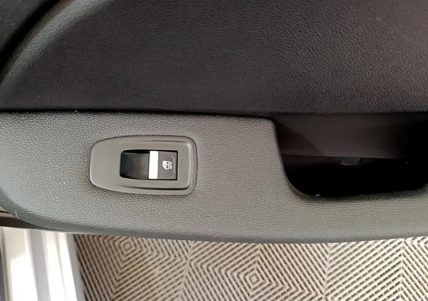 Gros plan sur le bouton de lève-vitre arrière droit dans l'habitacle gris clair d'une Renault Clio Business TCe 100 2020.