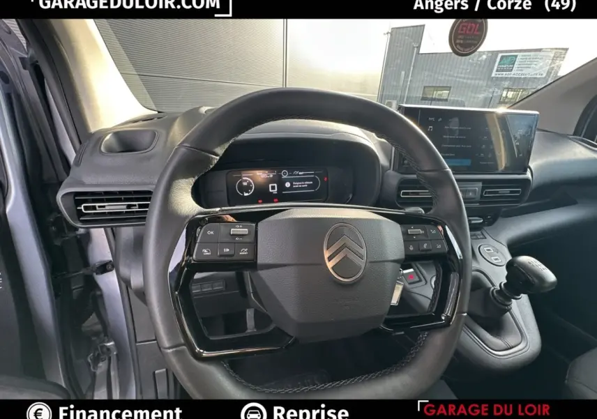 Vue intérieure centrée sur le volant cuir multifonctions et le combiné numérique du Citroën Berlingo gris clair 2024.