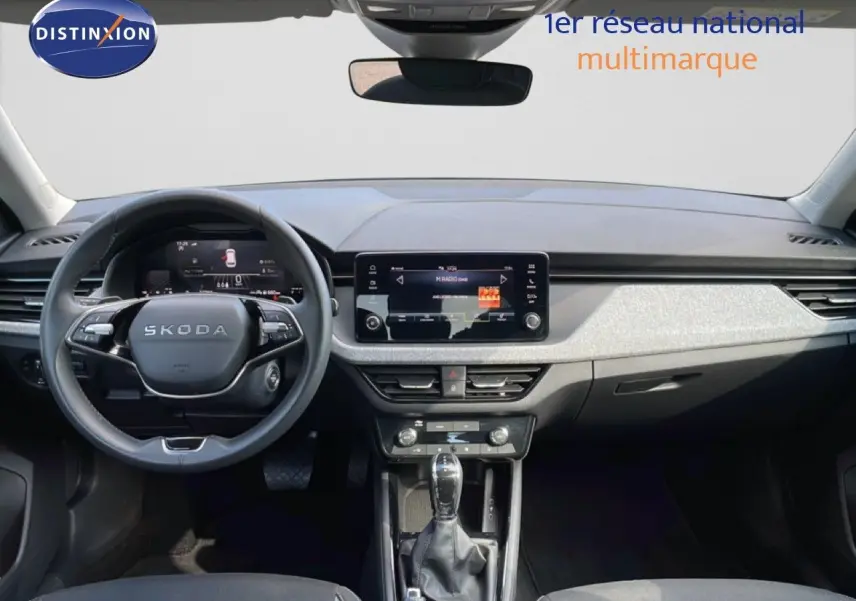 Vue intérieure frontale du Skoda Kamiq gris argent métal 2025, mettant en valeur le tableau de bord et l’écran tactile central.