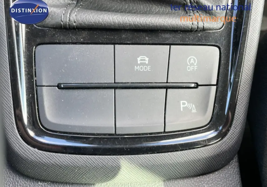 Gros plan sur les boutons de commande du mode de conduite et assistance au stationnement du Skoda Kamiq gris argent 2025.
