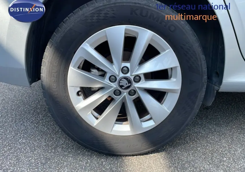 Gros plan sur la roue avant droite d’un Skoda Kamiq gris argent métal avec jante alliage et logo central visible.