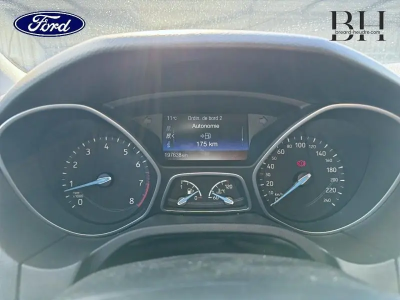 Vue rapprochée du tableau de bord de la Ford Focus 2016, affichant l'autonomie et compteurs numériques.