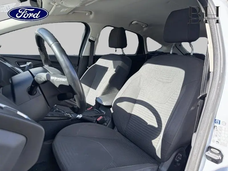 Intérieur avant de la Ford Focus blanc glacier 2016, sièges tissu noir et volant cuir multifonction côté conducteur.