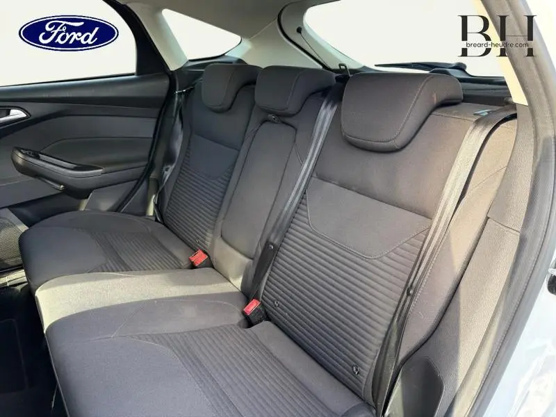 Vue intérieure sur la banquette arrière noire de la Ford Focus 2016 blanc glacier, avec ceintures et appuie-têtes visibles.