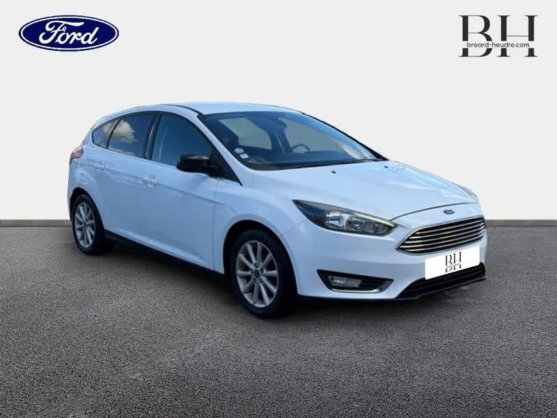 Ford Focus blanc glacier vue 3/4 avant droit avec calandre chromée et vitres arrière surteintées.