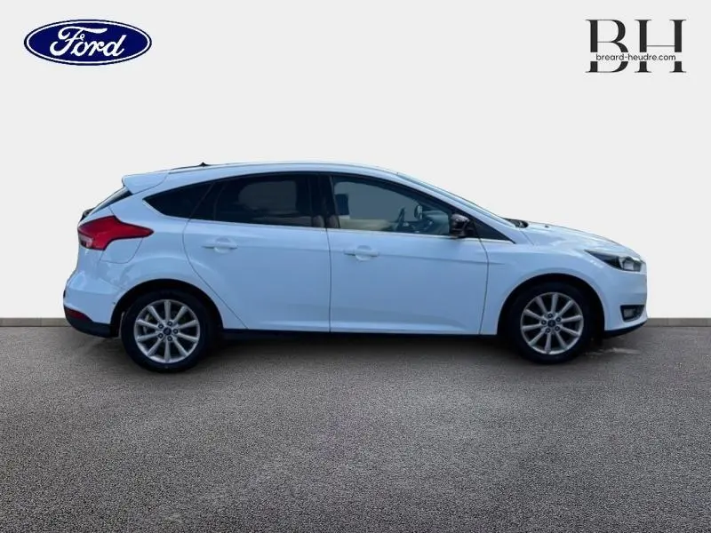 Vue latérale droite d'une Ford Focus blanc glacier de 2016 avec vitres arrière surteintées et jantes alliage.