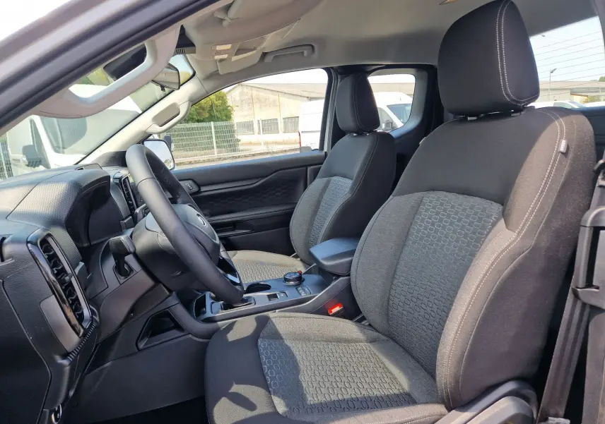 Vue intérieure côté conducteur du Ford Ranger Super Cabine gris Iconic, montrant les sièges avant et le tableau de bord.