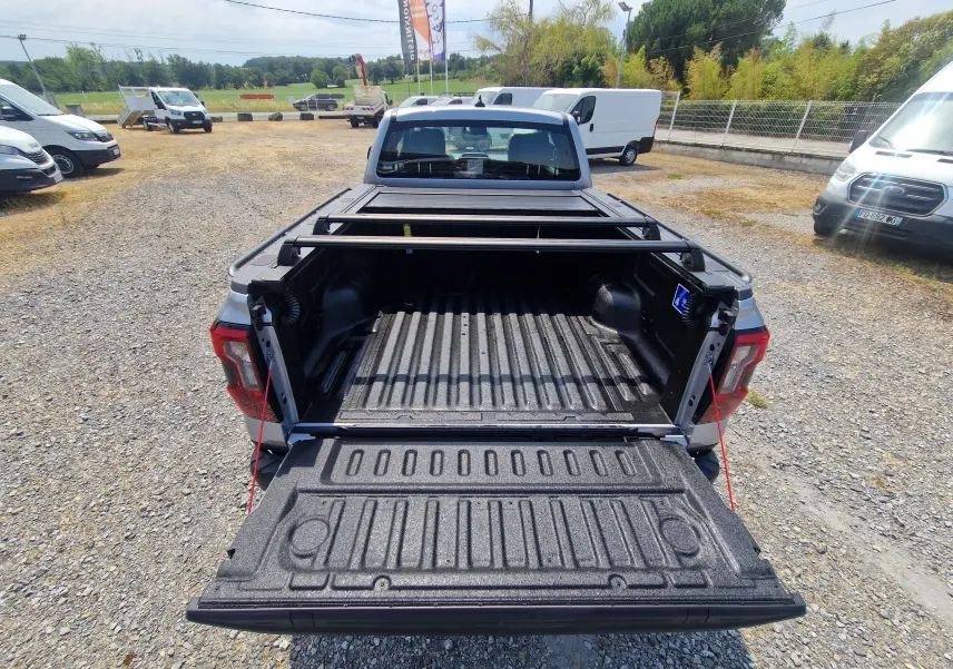 Vue arrière du Ford Ranger Super Cabine gris Iconic avec plateau ouvert, barres de renfort et rideau coulissant manuel visible.